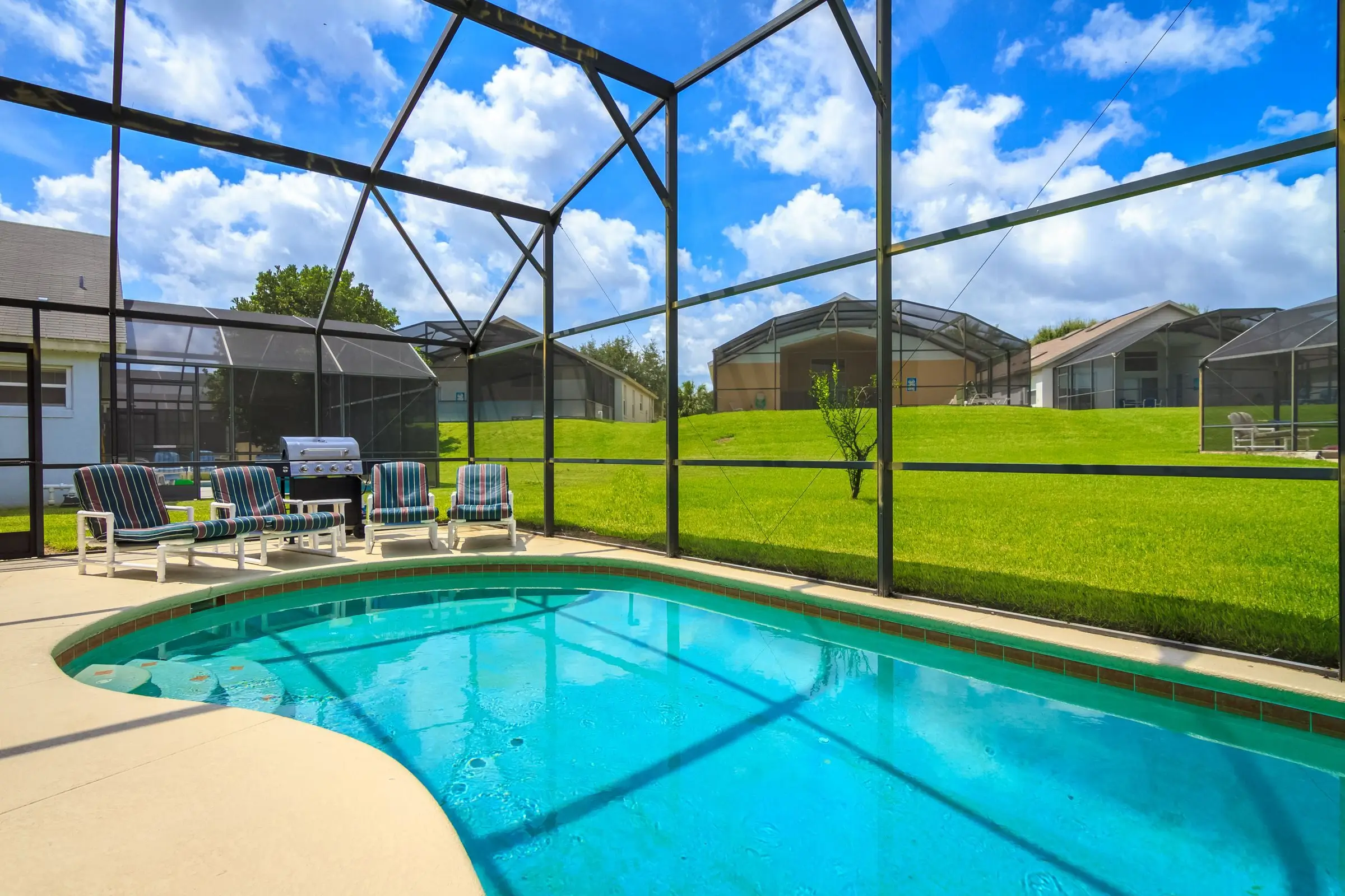 A screened pool enclosure with patio chairs
